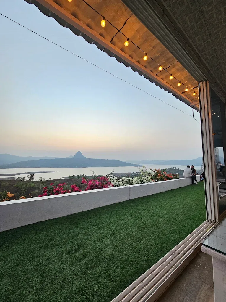 Warm interior of The Oven Lakeside restaurant glowing at sunset with panoramic Pawna Lake views