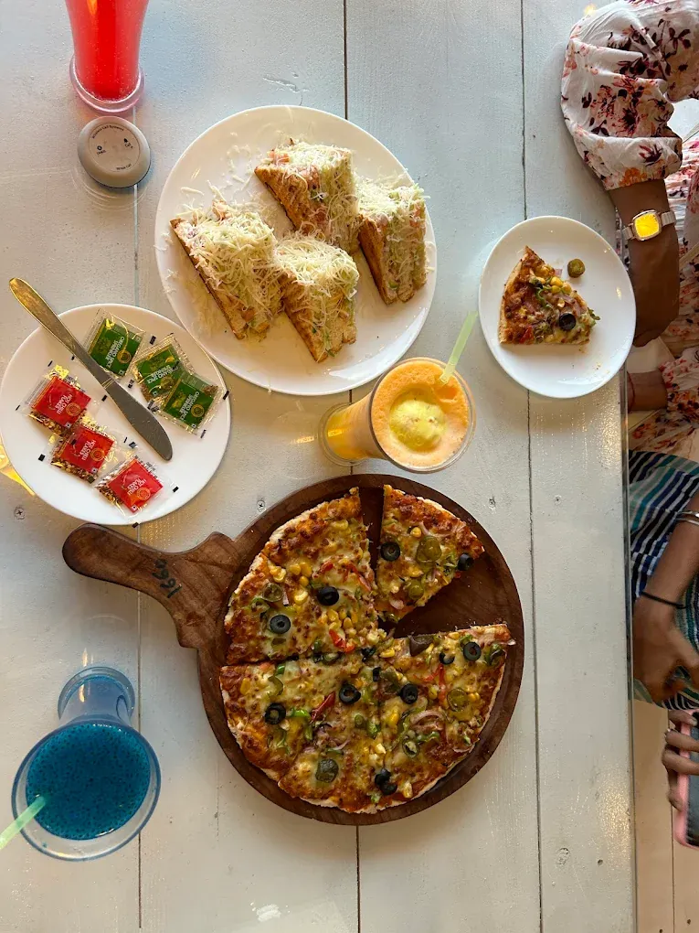 Top-down lakeside food spread with pizza and small plates at Pawna