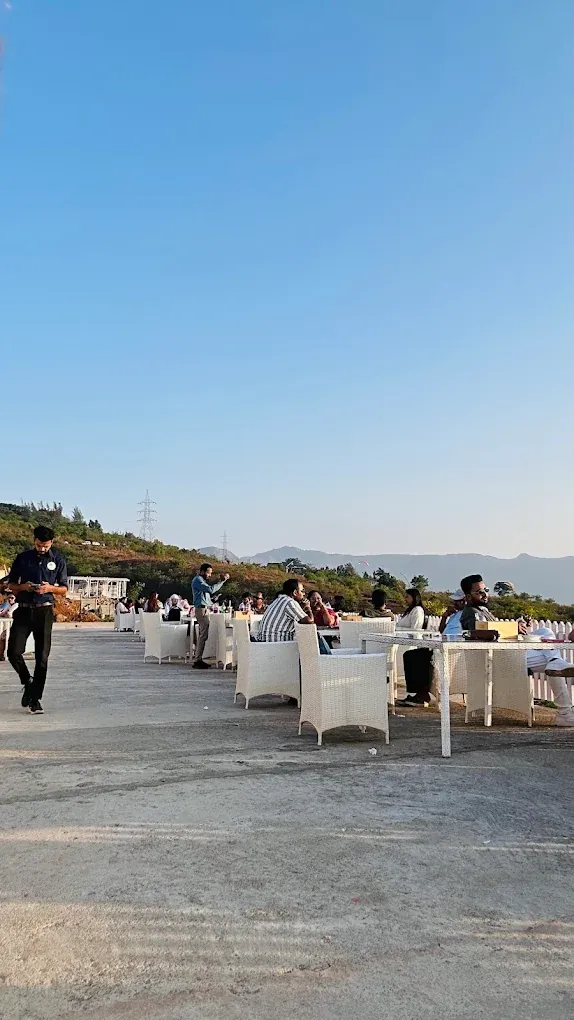 White tables set on the open-air lakeside deck in Pawna